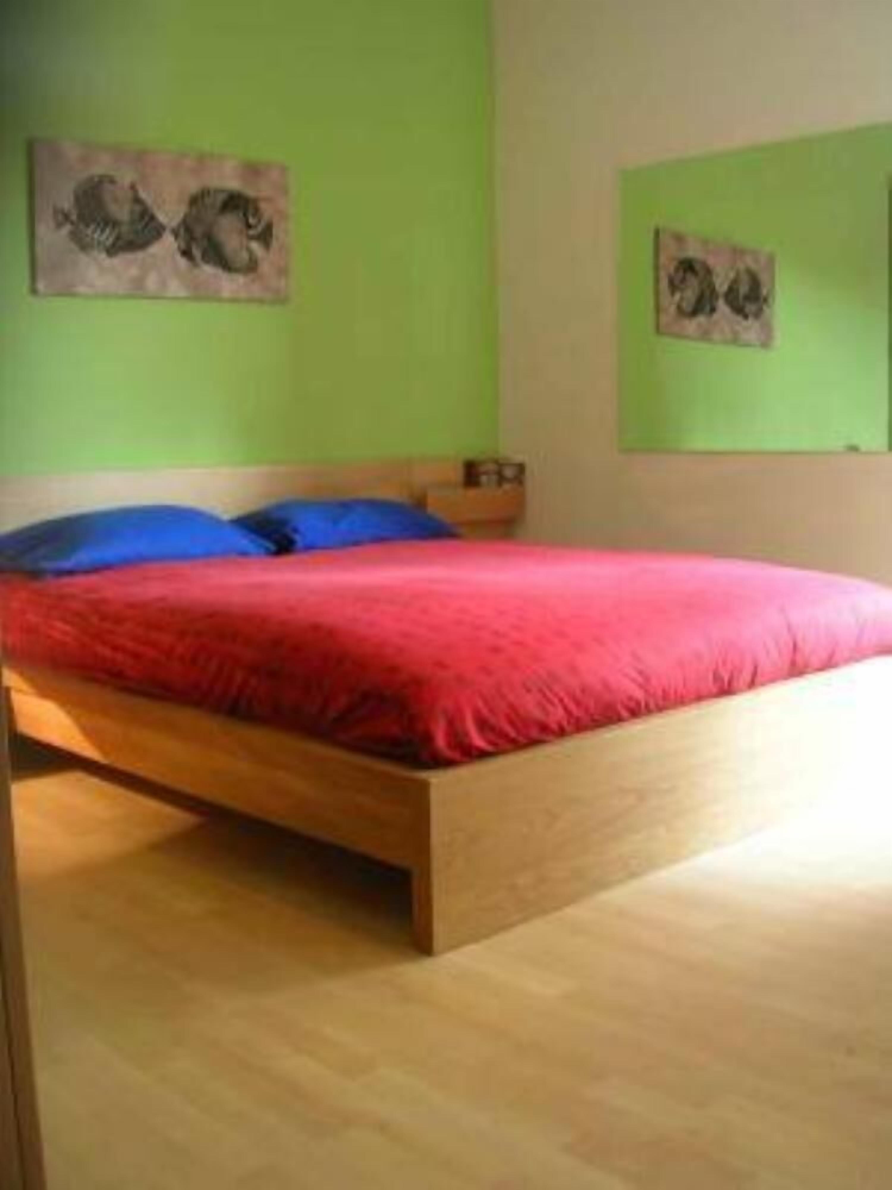 A bedroom with a wooden bed, red bedding, and green walls.
