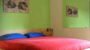 A bedroom with a wooden bed, red bedding, and green walls.
