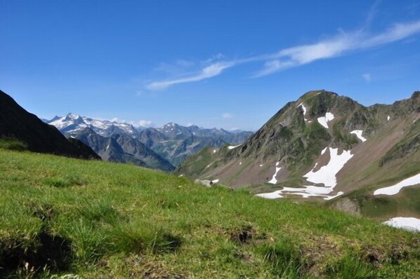 A mountainous landscape with grassy slopes and snow patches. - Large Apartment in the Hélios Residence (Barèges)