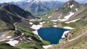 A mountainous landscape with a lake surrounded by snow patches and rocky terrain. - Large apartment in the Hélios residence (Barèges)