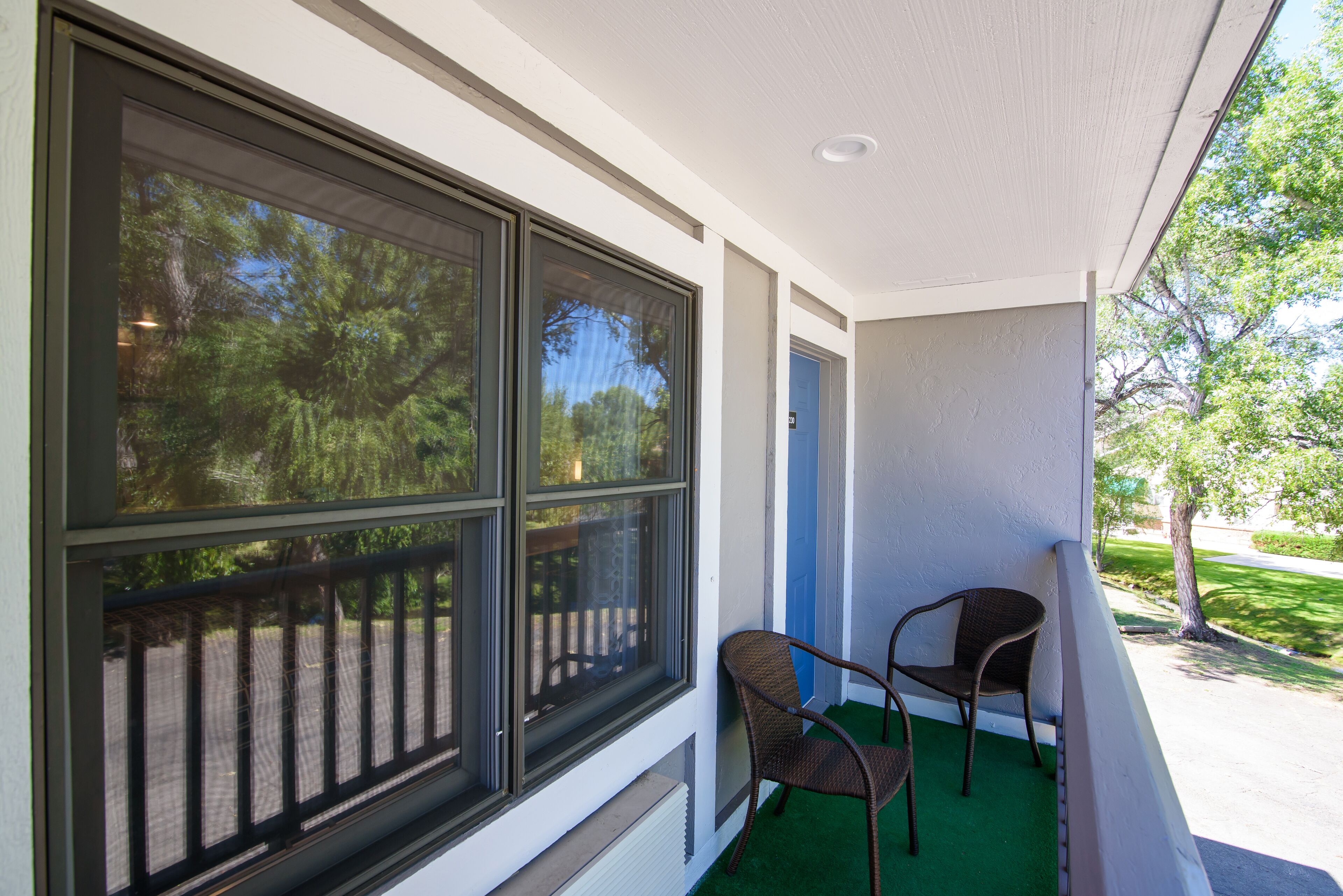 A balcony with large windows, a chair, and a door.