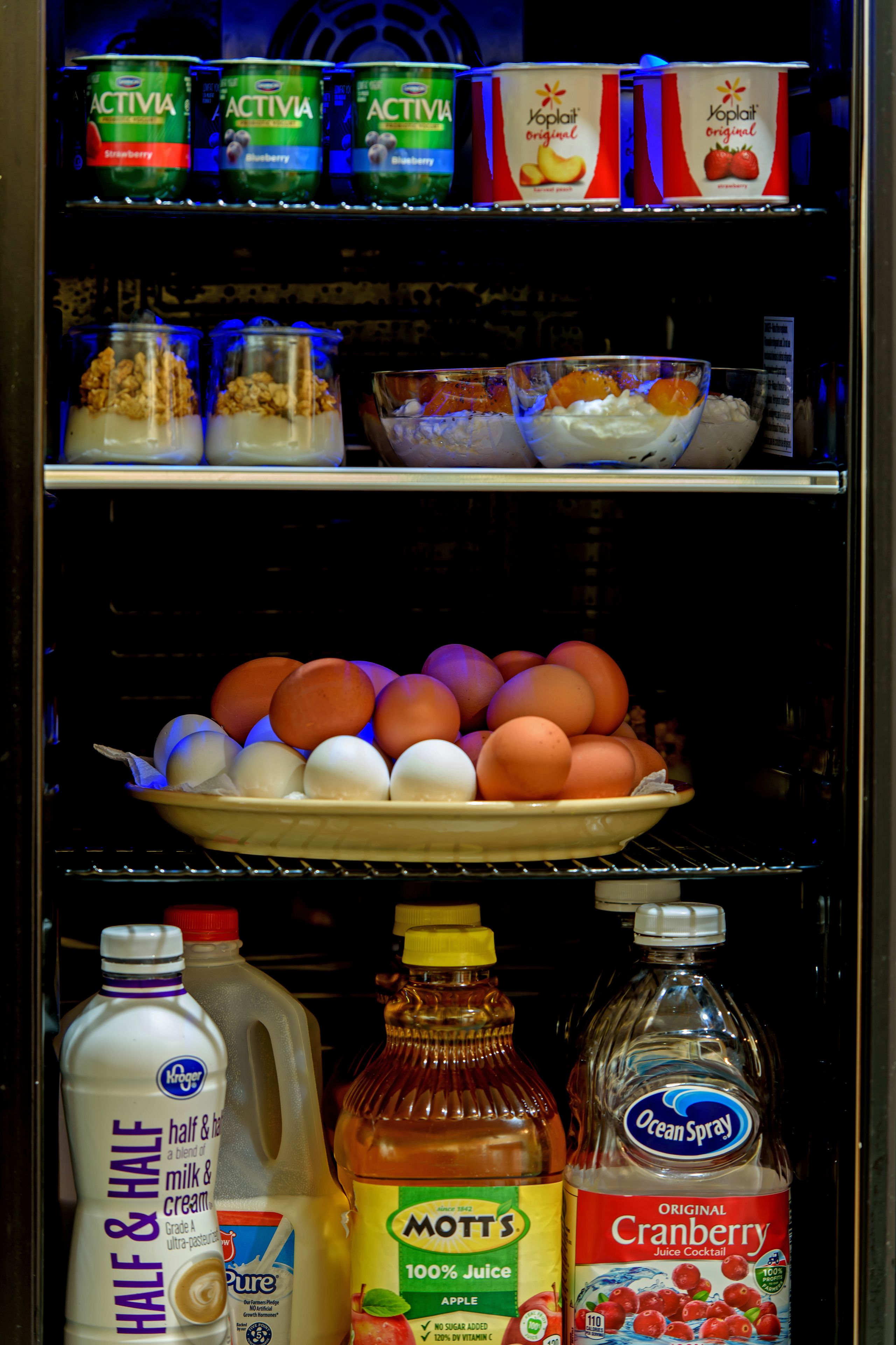 Un réfrigérateur rempli de divers aliments, notamment du yaourt, des œufs et des condiments.