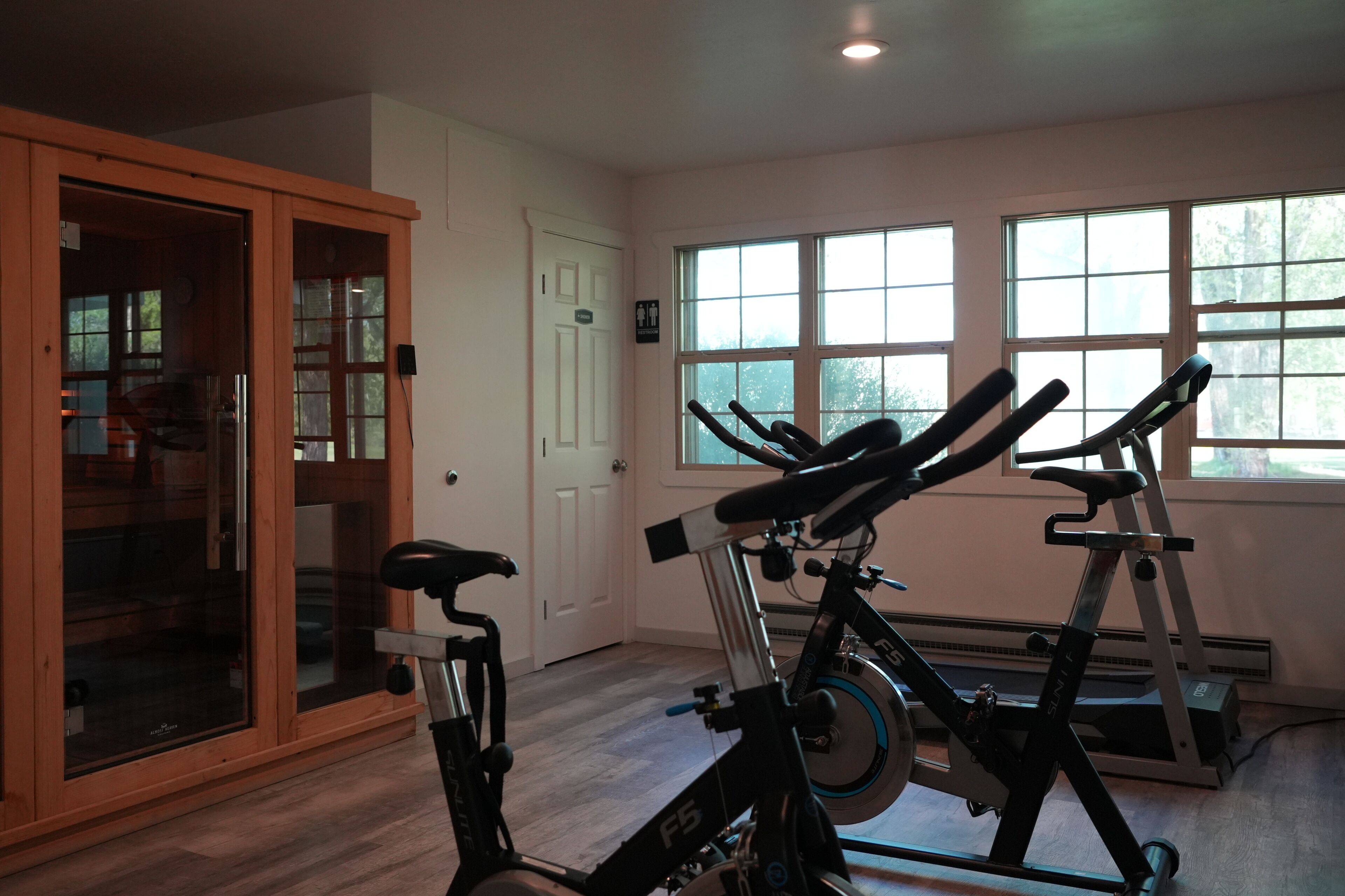 A room with a stationary bike, a treadmill, and a glass door leading to a balcony.