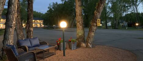 A serene outdoor seating area with a bench and a table, surrounded by trees and a street lamp.