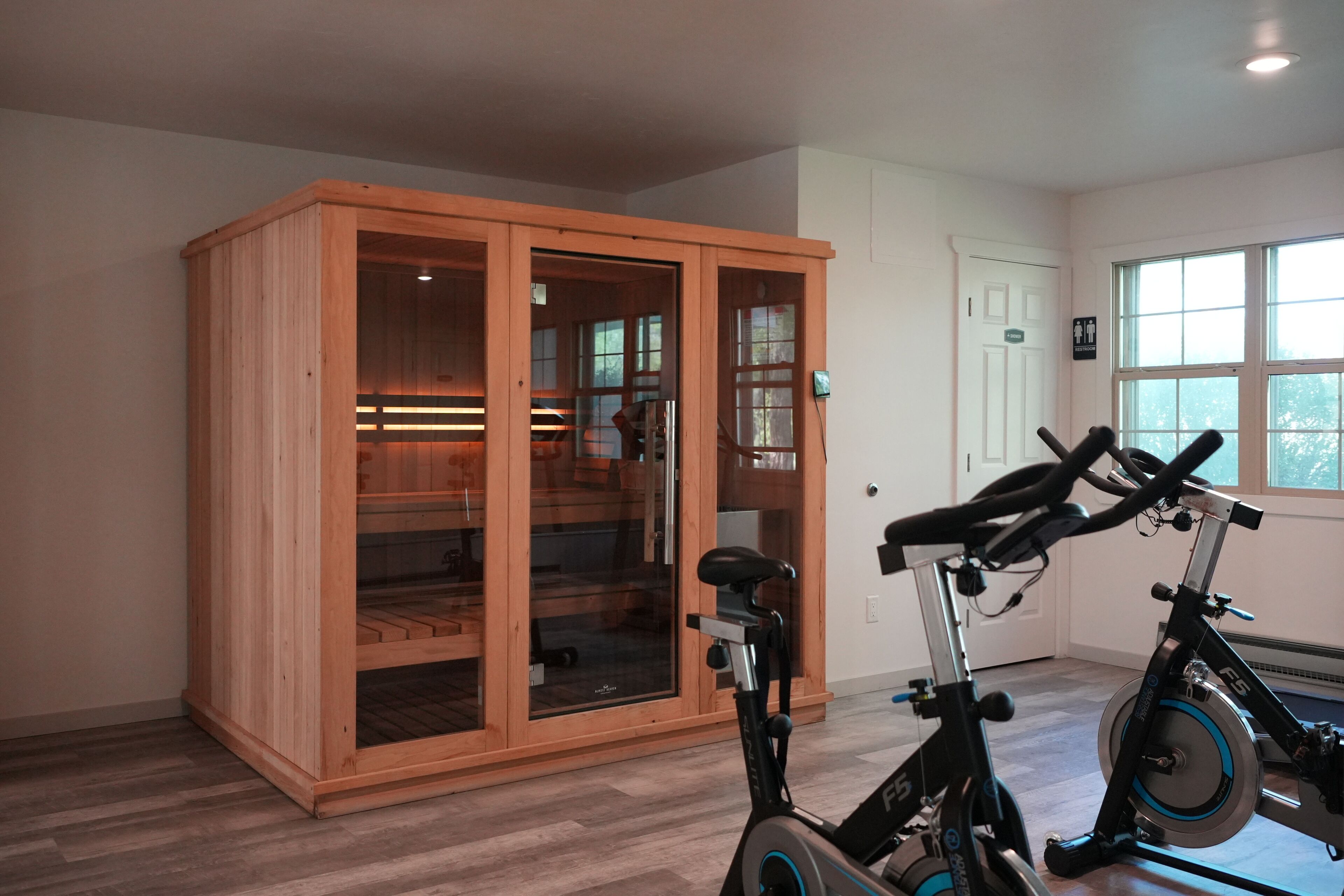 Una habitación con un armario de madera, una bicicleta estática y una ventana.