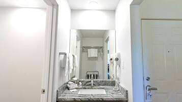 A hotel bathroom with a marble sink, a towel rack, a mirror, and a door with a "Please do not disturb" sign.
