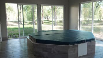 A room with a large sliding glass door leading to a backyard, a built-in bench with a mattress, and a tiled floor.