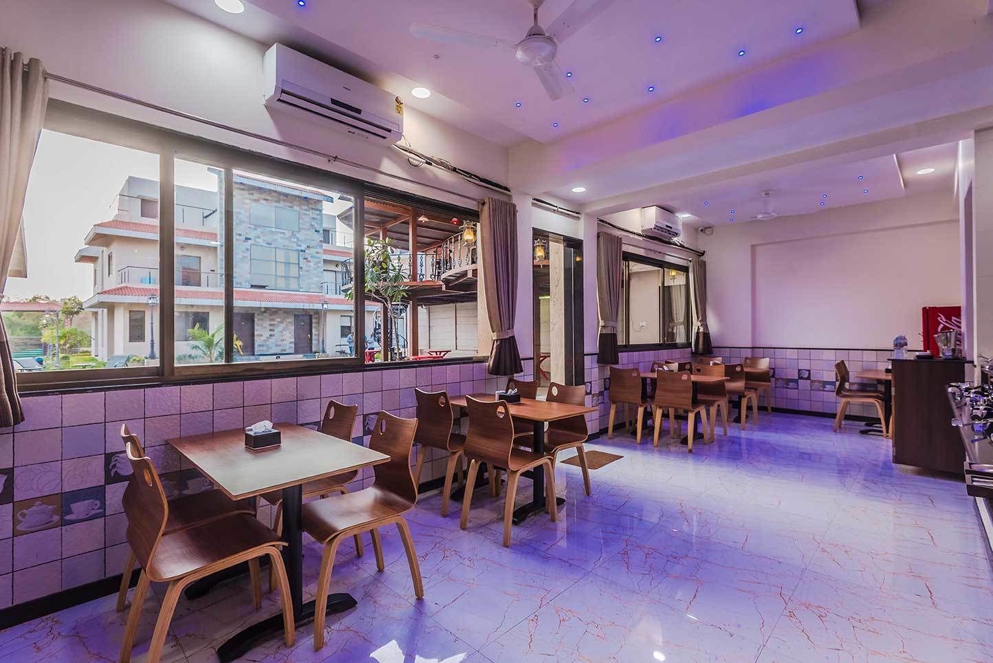 A restaurant with multiple tables and chairs, large windows, and an air conditioning unit on the ceiling.