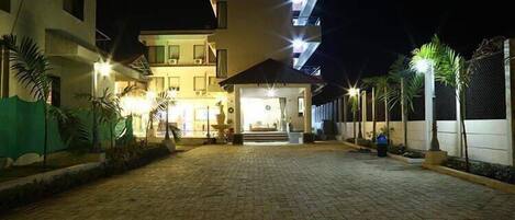 A two-story building with a paved courtyard, outdoor lighting, and a gated entrance.