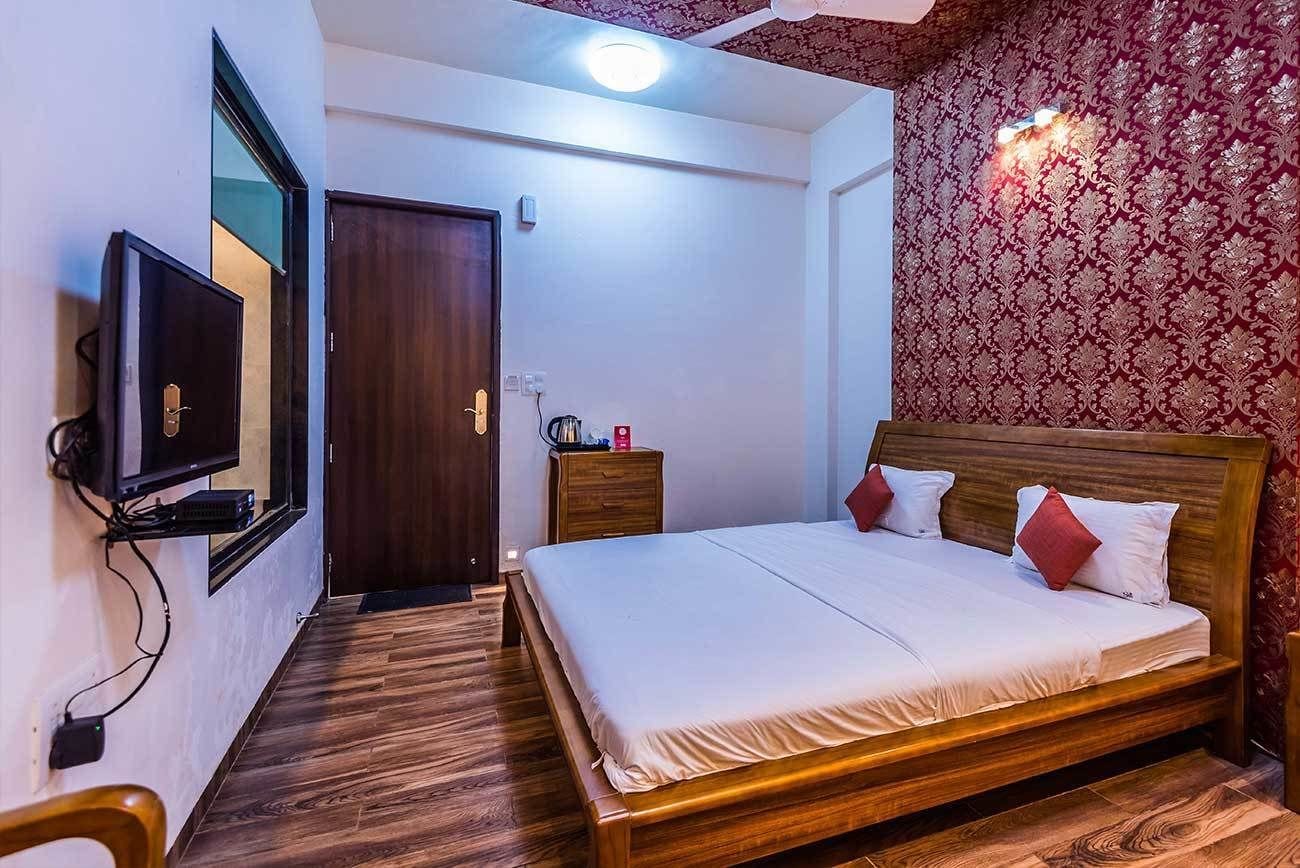 Una camera da letto con un letto di legno, una TV montata a parete e carta da parati decorata.