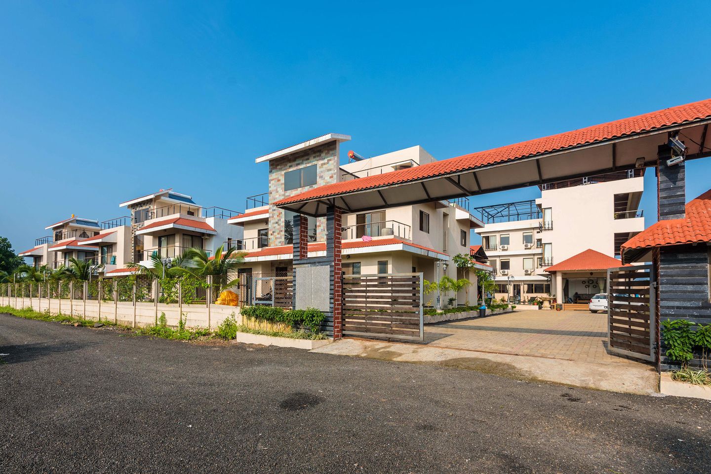 Un complejo residencial moderno con varias casas de dos pisos, cada una con techo de tejas rojas y entrada cubierta.