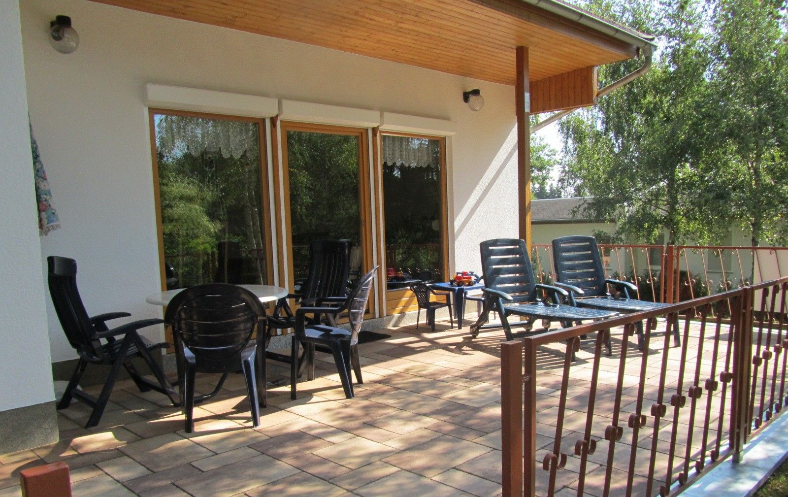 Un espace extérieur aménagé en terrasse, avec une table et des chaises, un coin salon couvert et une rambarde.