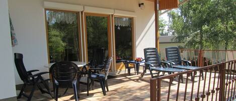Un espace extérieur aménagé en terrasse, avec une table et des chaises, un coin salon couvert et une rambarde.