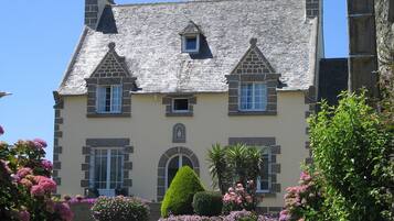 Un bâtiment en pierre doté d’une façade symétrique, de nombreuses fenêtres et d’une entrée centrale.
