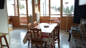 A dining area with a table and chairs, a sofa, and a view of the outdoors.