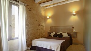 A bedroom with a wooden headboard, two bedside lamps, a bed with a white and brown bedspread, and a window with white curtains. - GITE SAINT-AMAND AT FELICIE (Le Bugue)