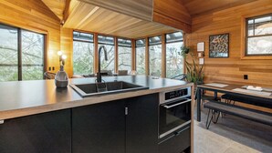 Una cocina moderna con una isla grande, horno empotrado y un comedor con mesa y sillas.