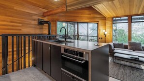 Una cocina moderna con una isla central, electrodomésticos de acero inoxidable y grandes ventanales con vistas al exterior.