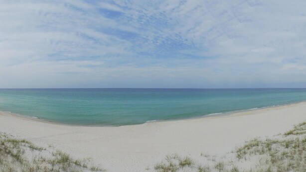 Ein Strand mit weißem Sand und einem klaren, blauen Himmel.