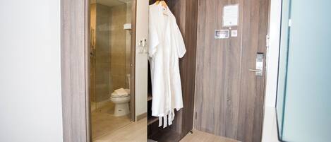 Un baño con cabina de ducha de vidrio, un inodoro y un mueble de tocador de madera con toallero.