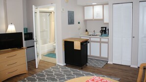 A compact hotel room with a kitchenette, a bathroom with a shower, a dining area, and a small table with a chair. - Enjoy Wonderful, Twelfth Floor Ocean/City Views Studio w/Kitchenette (North Myrtle Beach)