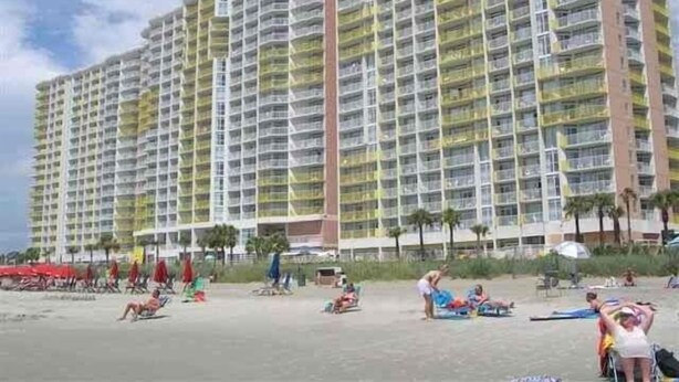 A high-rise hotel with multiple balconies, a beach in the foreground, and palm trees. - Enjoy Wonderful, Twelfth Floor Ocean/City Views Studio w/Kitchenette (North Myrtle Beach)