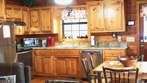 A wooden kitchen with a refrigerator, microwave, sink, and wooden cabinets. - YOUR mountain experience in this luxurious amenity galore cabin in the woods! (Blue Ridge)