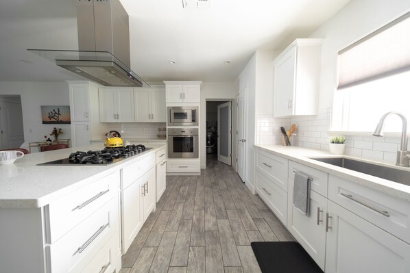 A modern kitchen with white cabinetry, stainless steel appliances, and a tiled backsplash. - Upscale & Modern Phoenix 2900 sqft Home w/ Heated or Chilled Pool by Scottsdale (Phoenix)