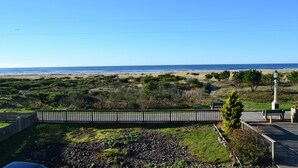 Vista sulla costa con spiaggia, zone verdi e un percorso che conduce a una zona con panchine.