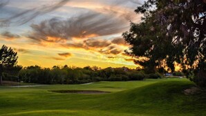 A golf course with a flagstick, trees, and a sunset sky. - Ace`s Cowboy Condo with a view (Phoenix)