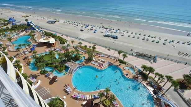 Ein Resort mit großem Swimmingpool, Strandbereich und Wasserrutsche.