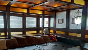 Un interior moderno con un sofá de cuero oscuro, ventanas amplias con vidrio texturizado y una lámpara colgante.