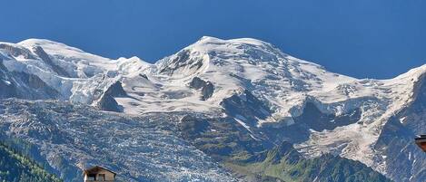 A mountain landscape with snow-covered peaks and a clear blue sky.