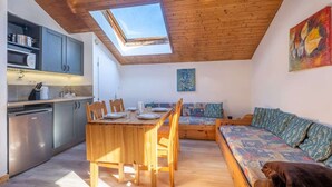 A compact living space with a skylight, a kitchenette, a dining area, and a sofa.