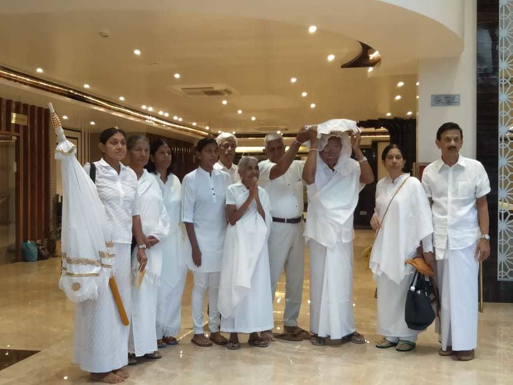 A group of people in a hotel lobby with a modern design, including a marble floor and a curved ceiling.
