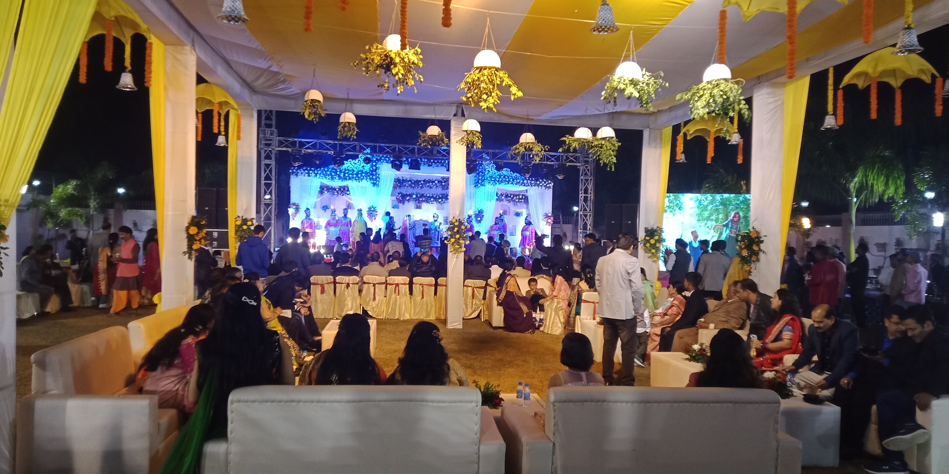 A decorated indoor event space with a stage, seating, and hanging decorations.