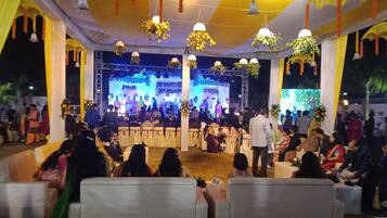 A decorated indoor event space with a stage, seating, and hanging decorations.