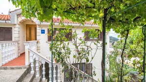 Un edificio con una escalera que lleva a un balcón, rodeado de vegetación y vistas al campo.