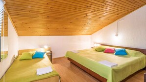 Una habitación con dos camas, techo de madera y paredes blancas.