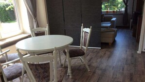 Un comedor con una mesa redonda y cuatro sillas, una pared oscura y vistas a un jardín a través de una ventana.