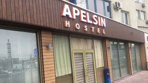 Et hostel kaldet "APELSIN HOSTEL" med store vinduer og en træfacade.