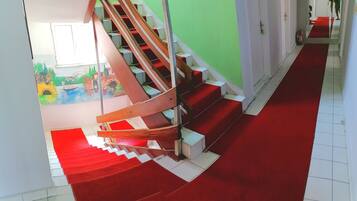 A staircase with red carpeted steps leading to a landing with a green wall and a white door.