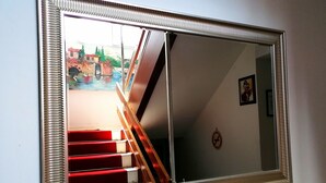 A large mirror with a ribbed frame reflecting a staircase and a small decorative item on a wooden shelf. - Mudanya Otel (Mudanya)
