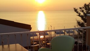 A terrace with a table and chairs overlooking the sea during sunset. - Mudanya Otel (Mudanya)