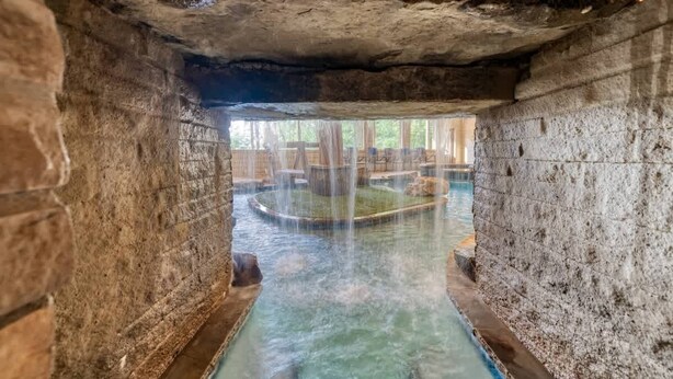 Un spa con paredes de piedra, un canal de agua cristalina y una pequeña piscina.