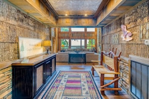 A rustic interior with a wooden ceiling, a sofa, a bench, and a stone wall.