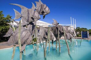 Stunning poolside art installation features large metallic fish sculptures.