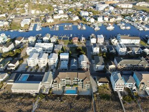 Stunning coastal neighborhood with marina, single-family homes, and apartment complexes surrounded by lush greenery.