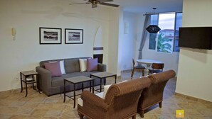 A living room with a grey sofa, two brown wicker chairs, a coffee table, and a TV mounted on the wall. - "Marietas", One bedroom Apartment. You can walk to Beach and Restaurants.  (Punta de Mita)