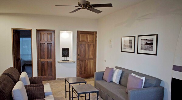 A living room with a grey sofa, a brown wicker sofa, a small table, and a ceiling fan. - "Marietas", One bedroom Apartment. You can walk to Beach and Restaurants.  (Punta de Mita)